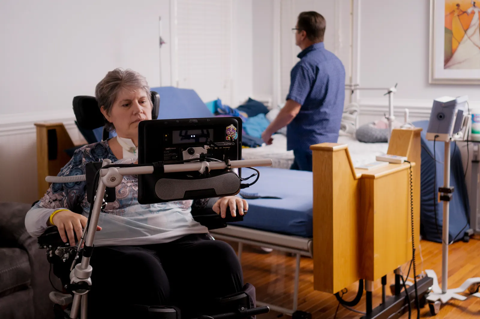 Two people are seen in a room with a medical bed.
