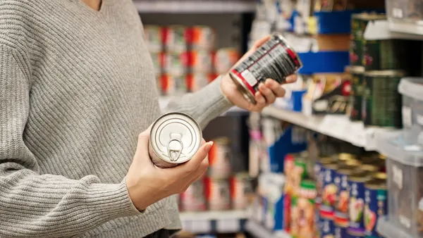 a person handles canned food in the aisle of a store