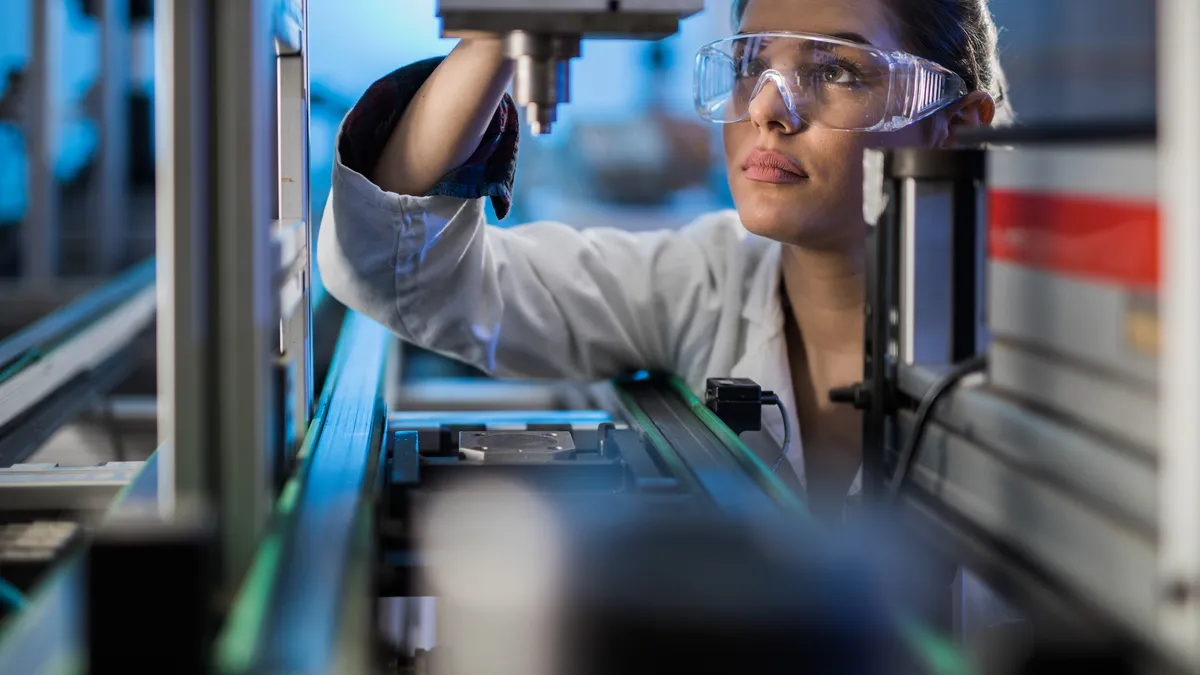 Quality control worker analyzing machine part on a manufacturing machine