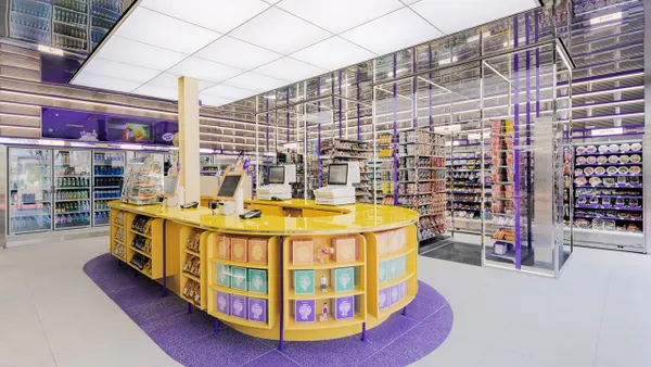 A photo of the interior of a store, showing the checkout area, shelves with snacks and coolers with drinks.