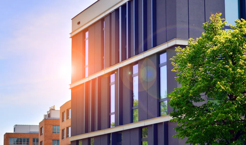 Eco architecture. Details of facade glass and aluminum panels on building. Green tree and modern office building.