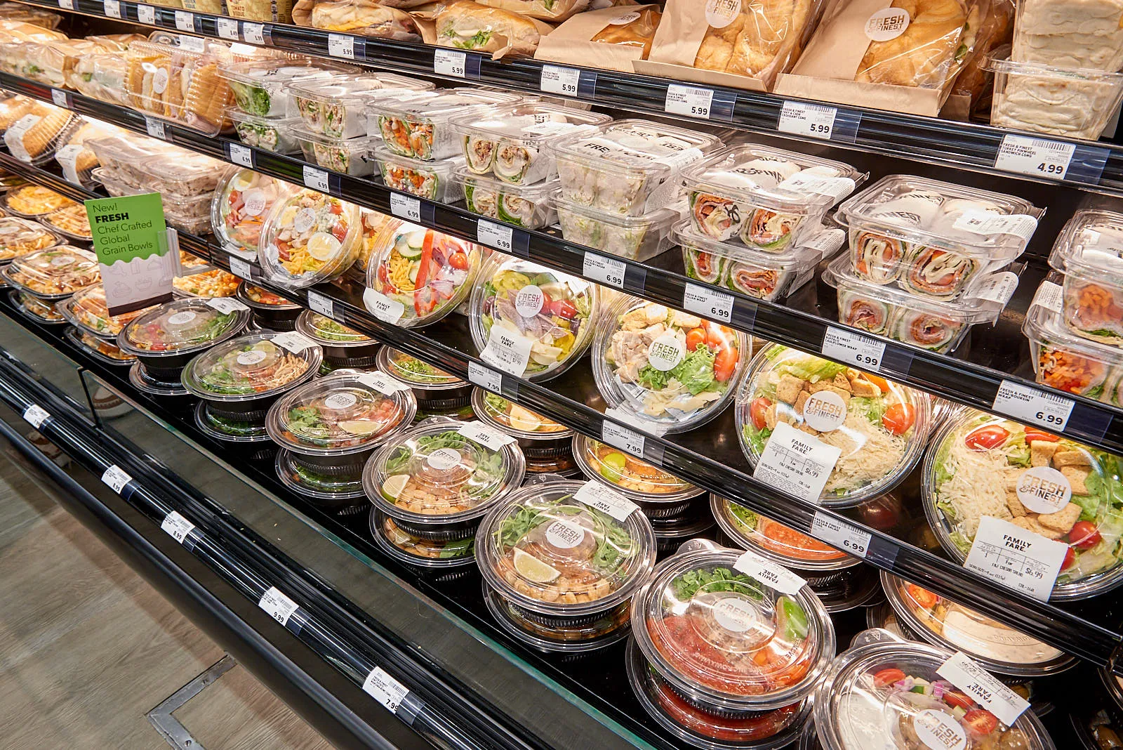 Prepared foods offering, including grain bowls and deli sandwiches packed in plastic to-go containers