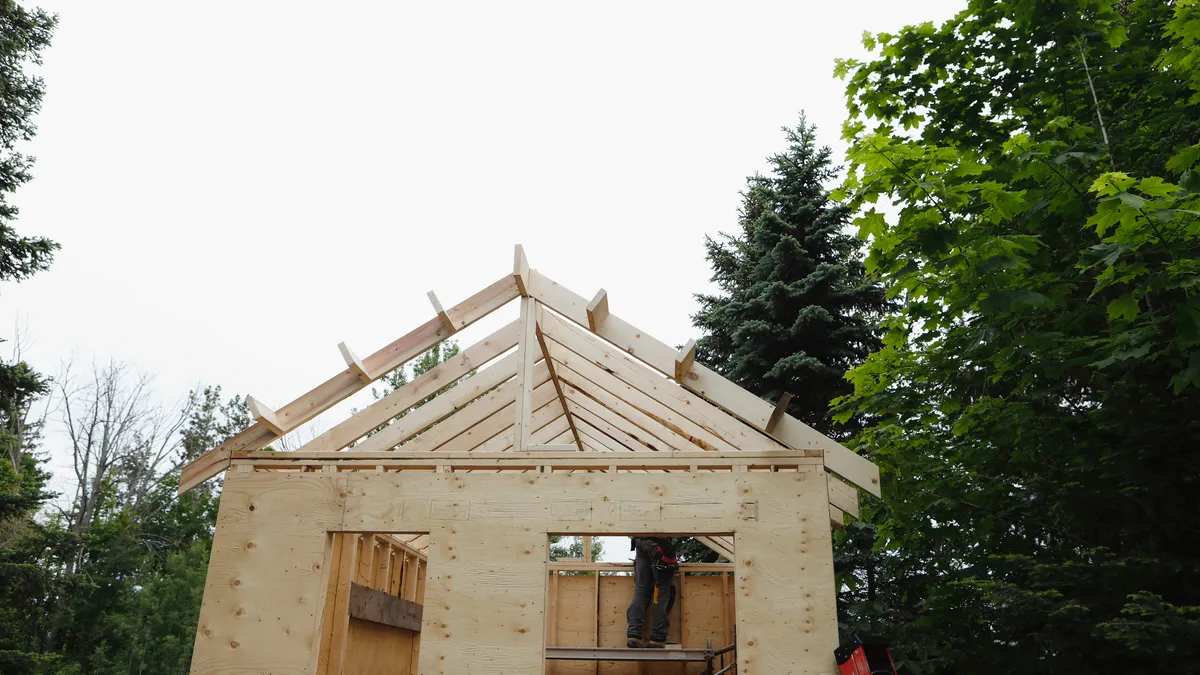 A man framing the roof of a small cabin