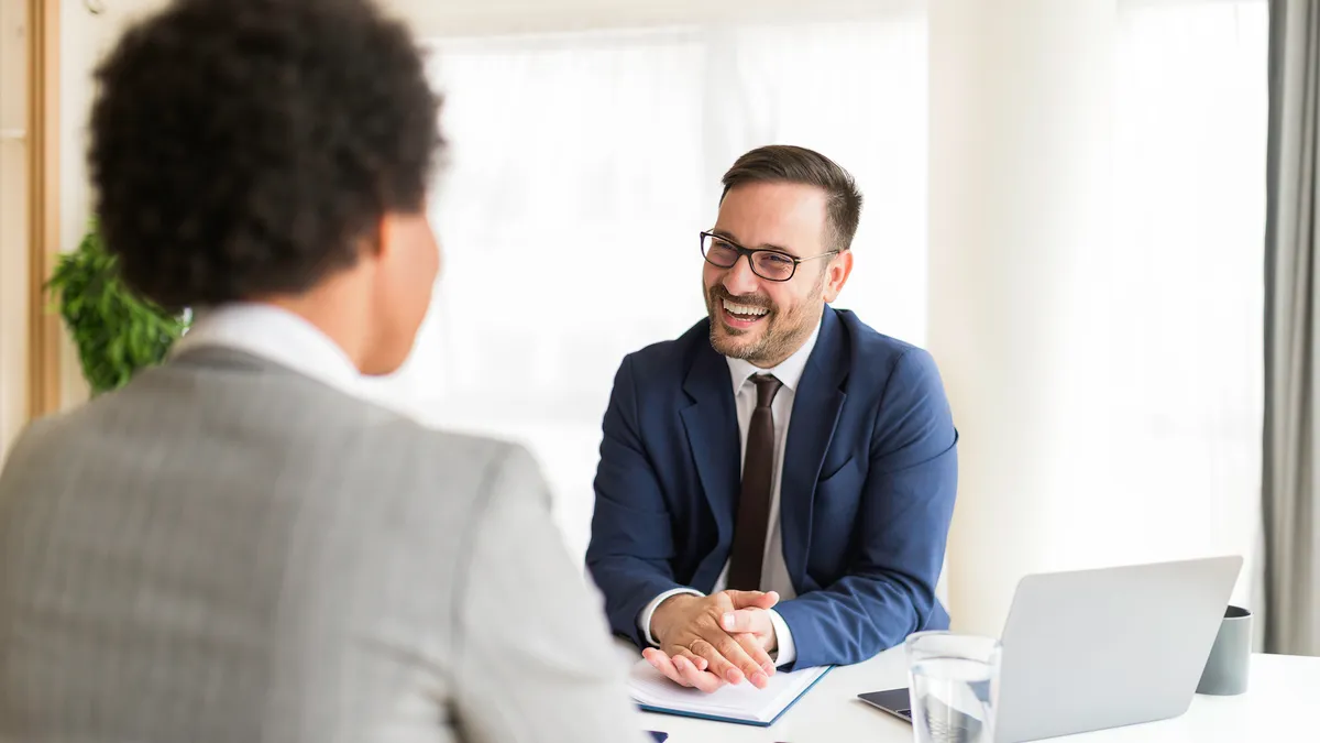 A smiling general counsel meets with a colleague in their office