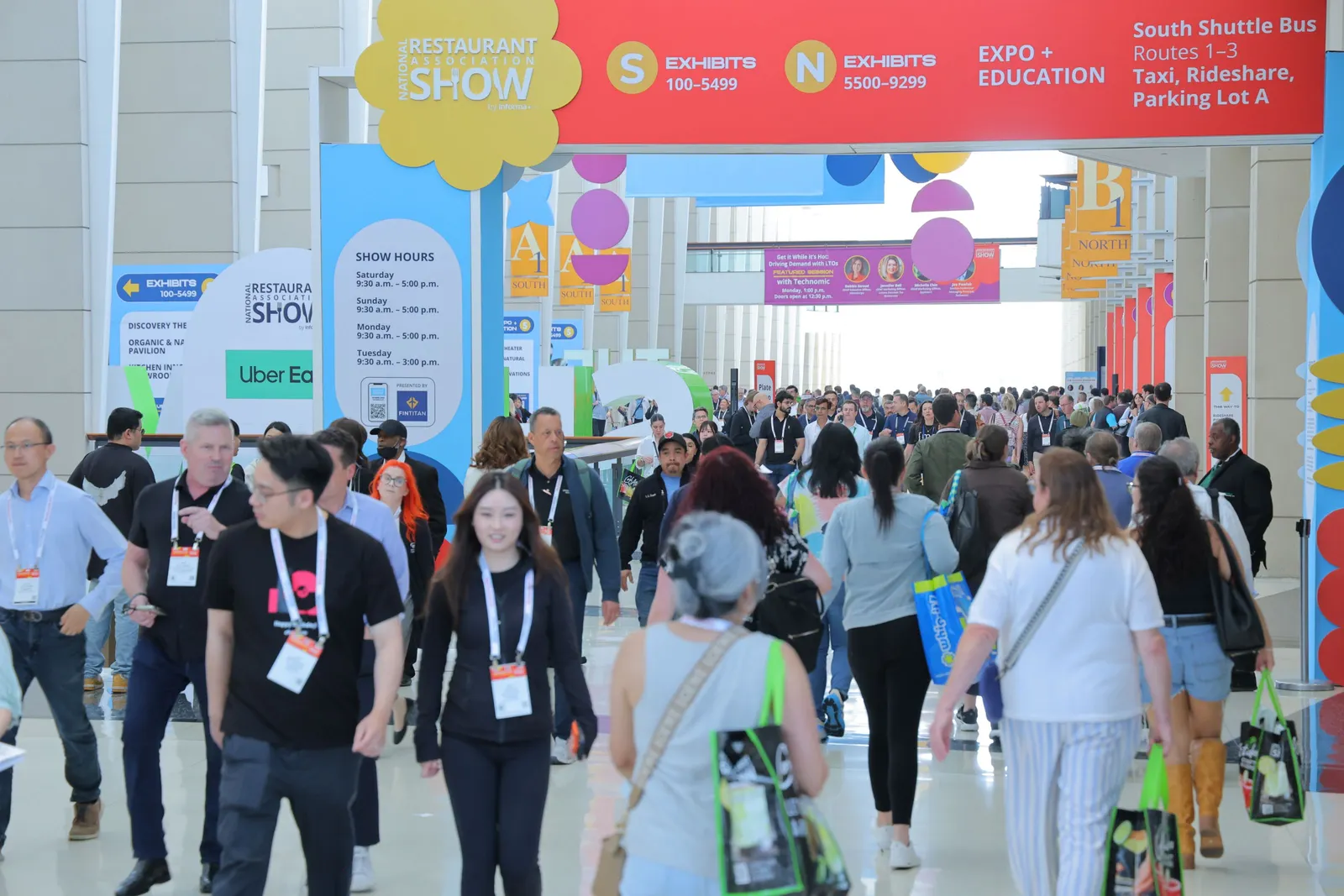A potograph of a group of people walking through a convention hallway. Signs say National Restuanat Association Show