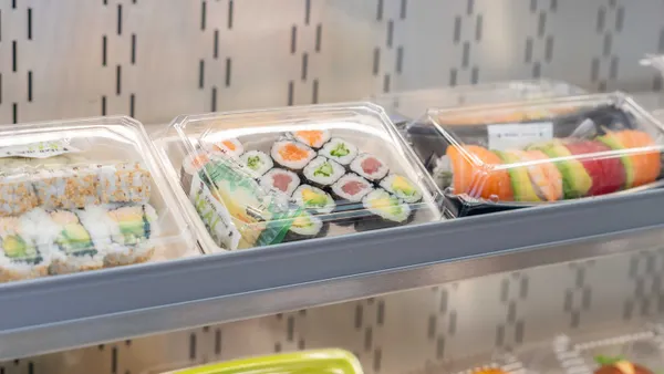 A photo of trays of suschi in plastic packaging inside a cooler case.