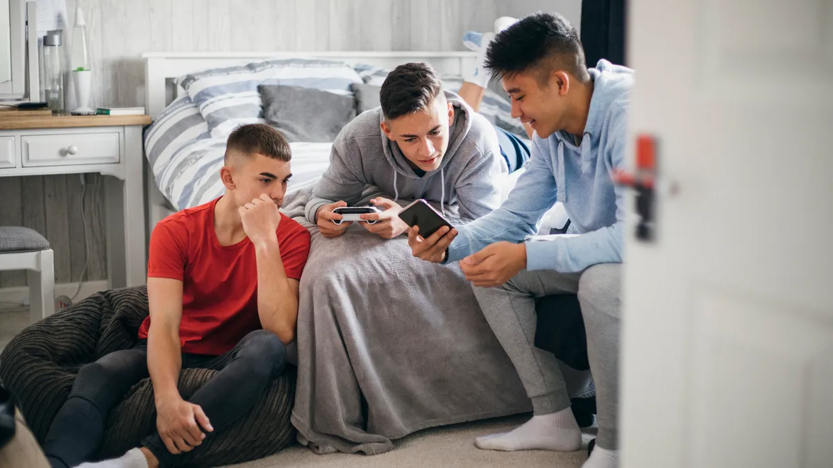 Three teens sit together while looking at a phone.