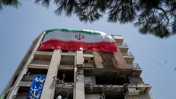 An Iranian flag hangs on the side of a damaged building