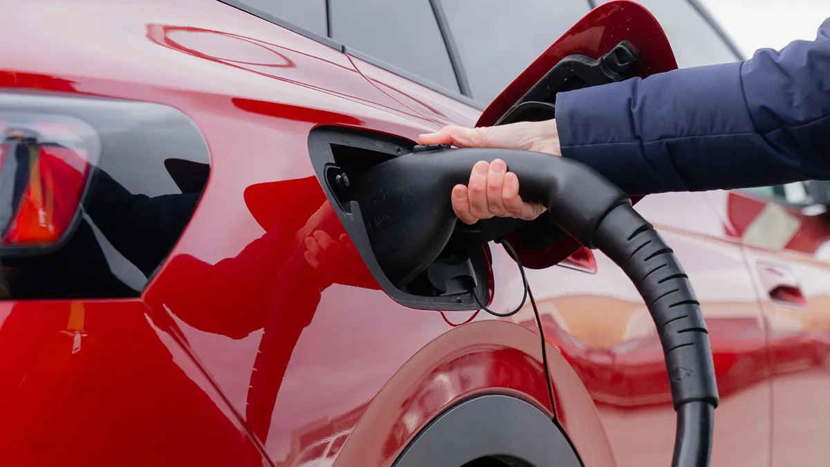 Man using EV charging machine to charge vehicle.