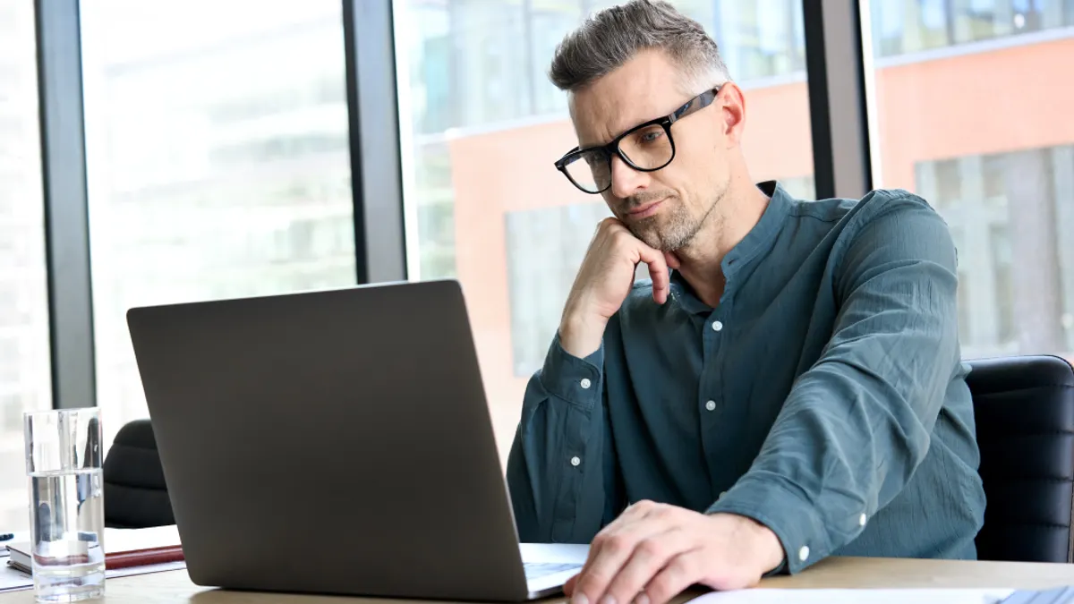 Focused businessman corporate leader ceo executive manager thinking of online planning, business analyst analyzing financial market strategy using laptop computer sitting at office table.