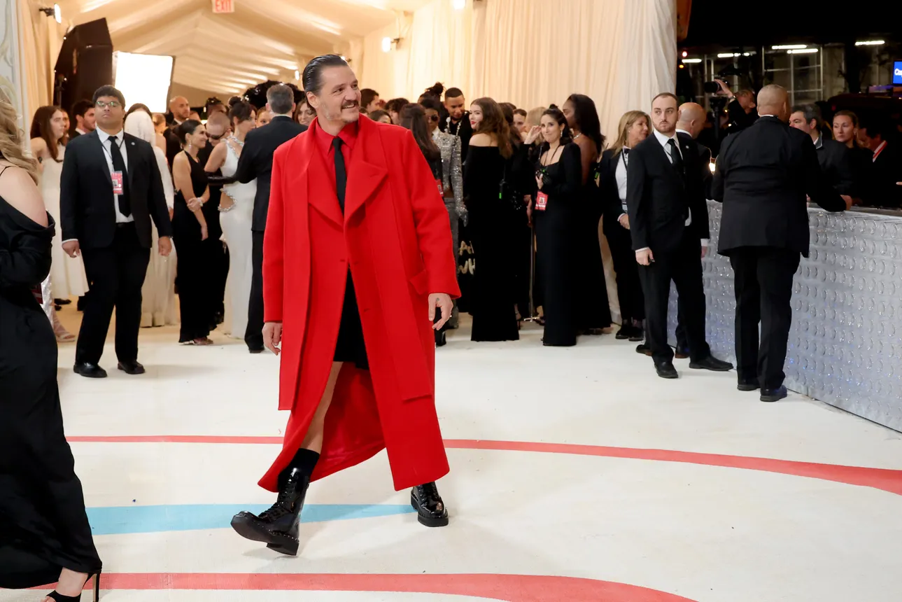 Man in red shorts suit smiles and walks in front of a crowd