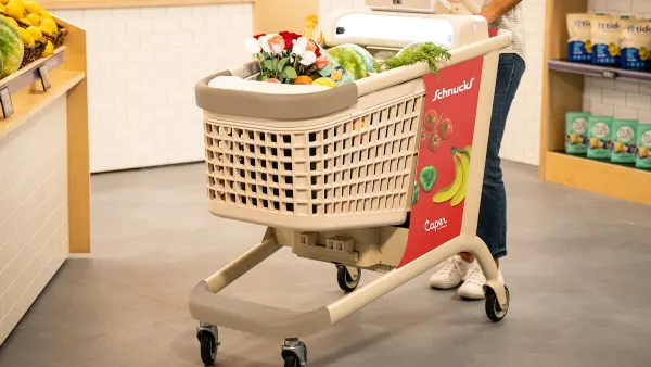 A shopper pushing a Schnucks-branded Caper Cart in a grocery store.