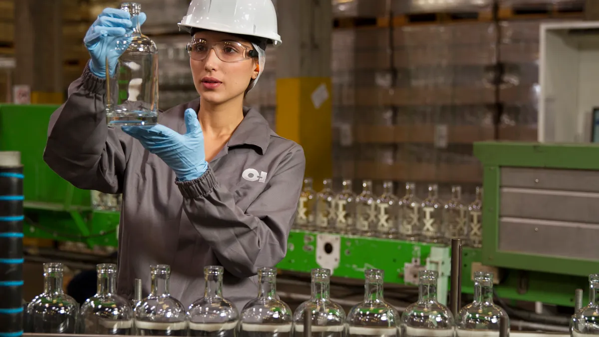 O-I Glass worker inspects glass bottles