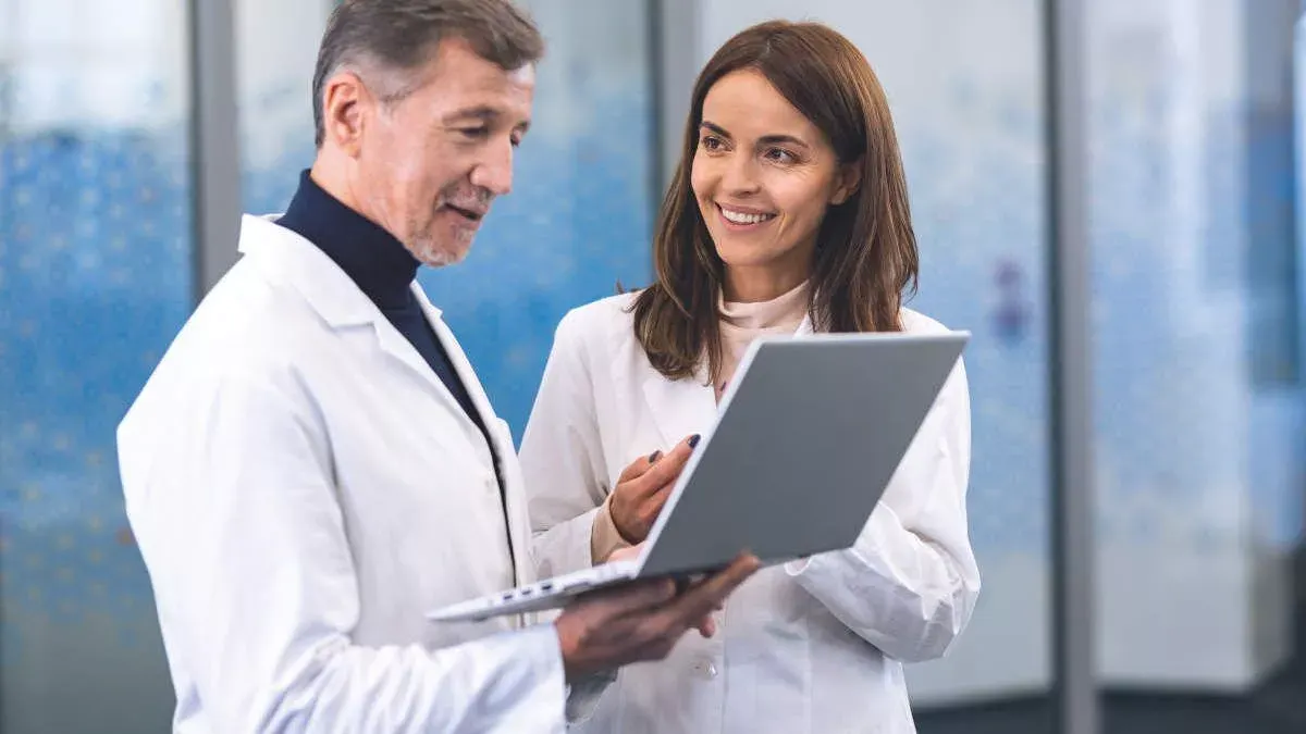 Male and female clinicians looking at laptop