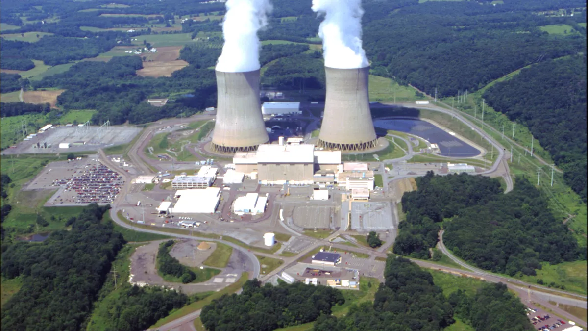 Steam billows from two cement cooling towers.