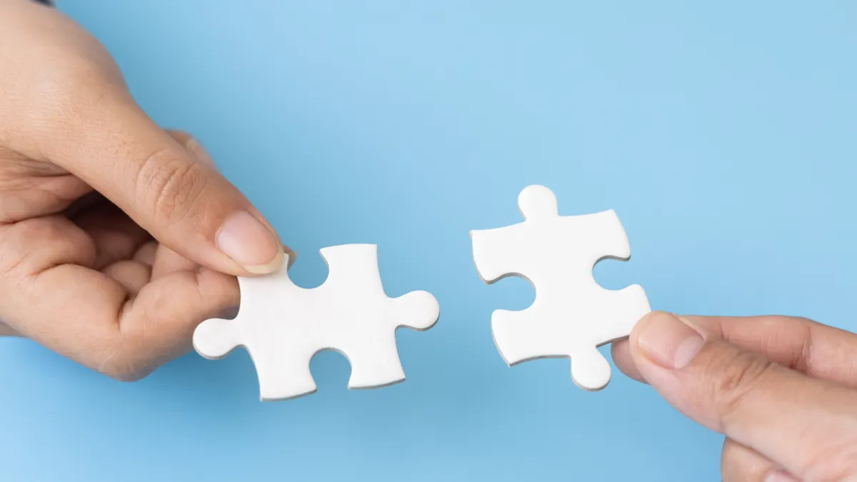 Business team holding parts of jigsaw puzzle trying to find solution to problem together. Concept of challenge and determination as the person works to complete the puzzle.