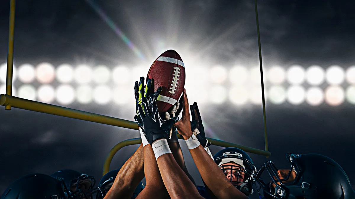 Victorious american football team holding up ball at night