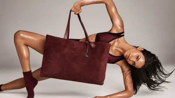 A person poses in a side plank while holding a large burgundy suede tote bag.