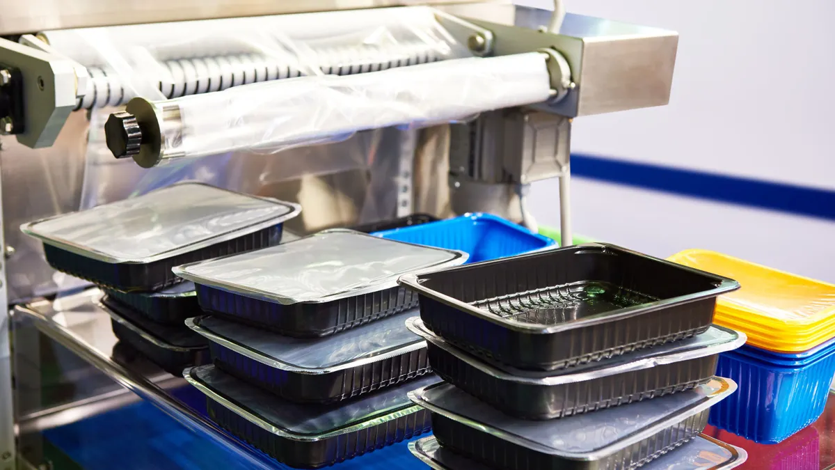 Stacks of black plastic food containers being packaged