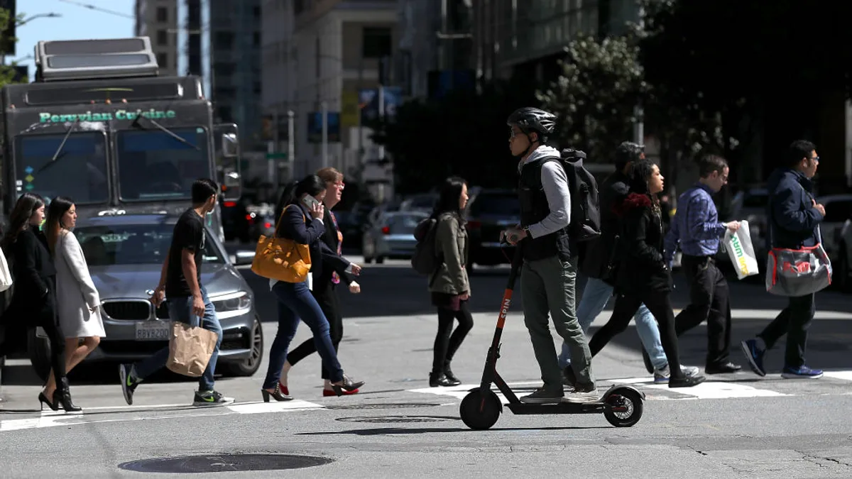 A person rides a scooter on a city crosswalk.