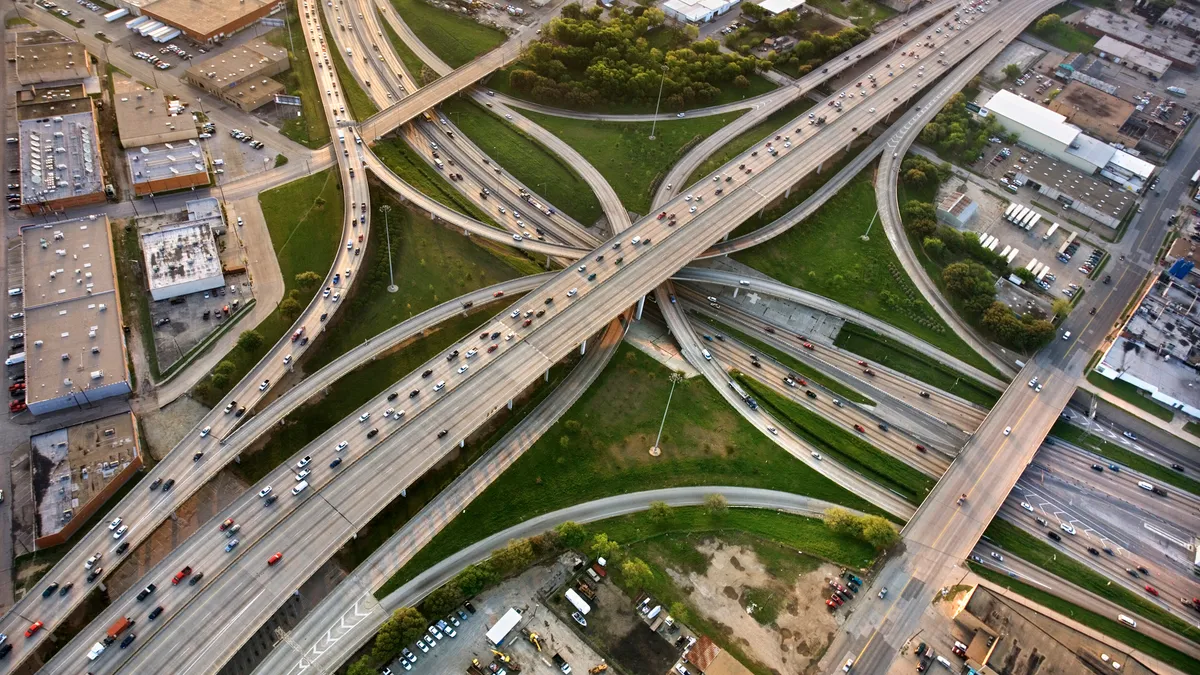 Cars and trucks fill lanes across highways in Dallas as shown from a sky-high overhead view.