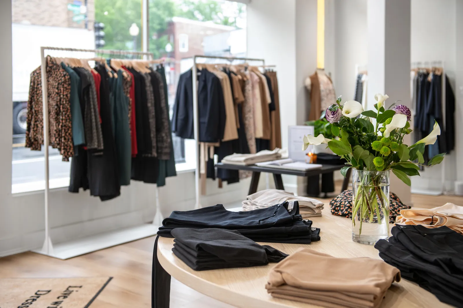 A round display table with a rack of clothing behind it, both displaying workwear.