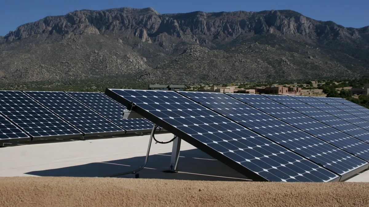 Solar panels on the ground with mountains in the background.