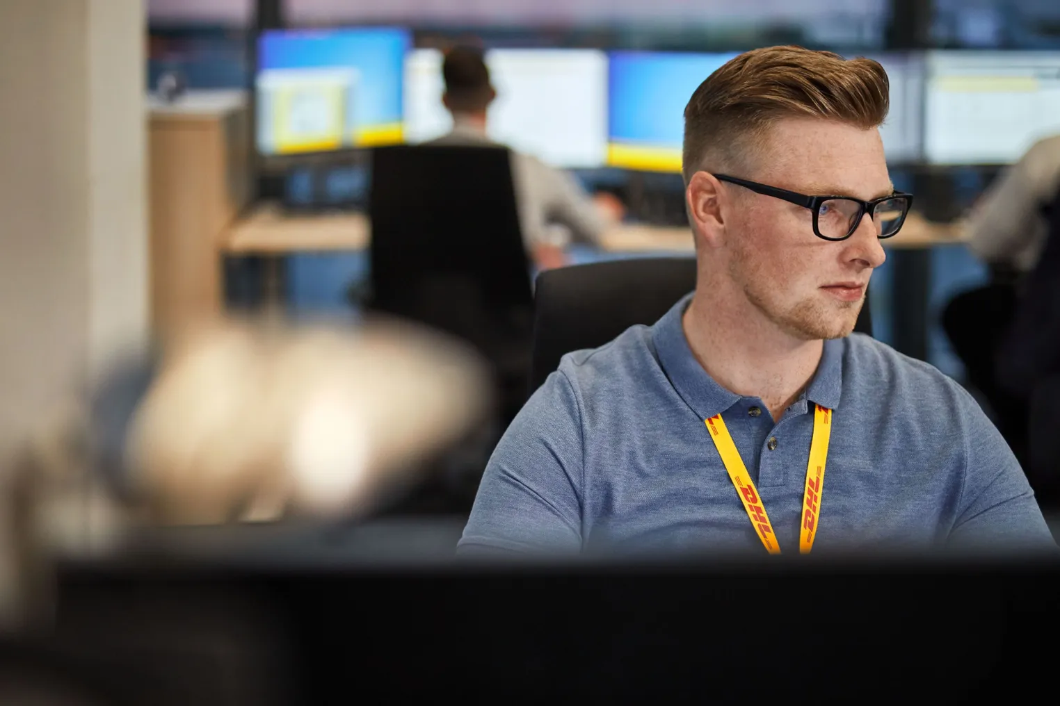 A DHL employee sits in front of a computer.