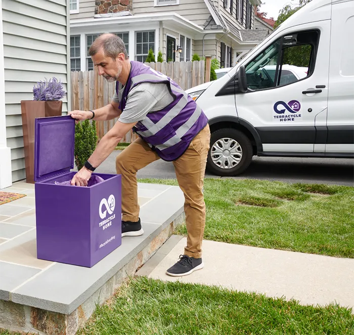 Person collecting a bag from a blue box, van in background