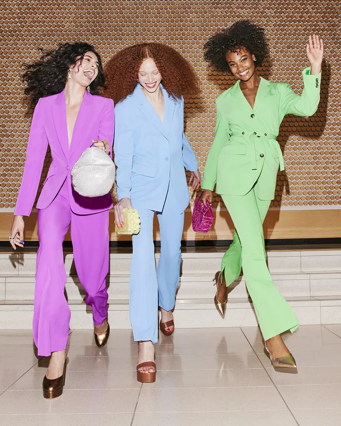 Three people in bright clothes laughing.