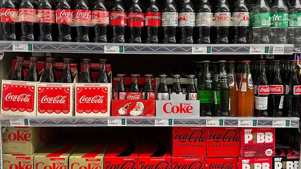 bottles of Coca-Cola are displayed on a store shelf