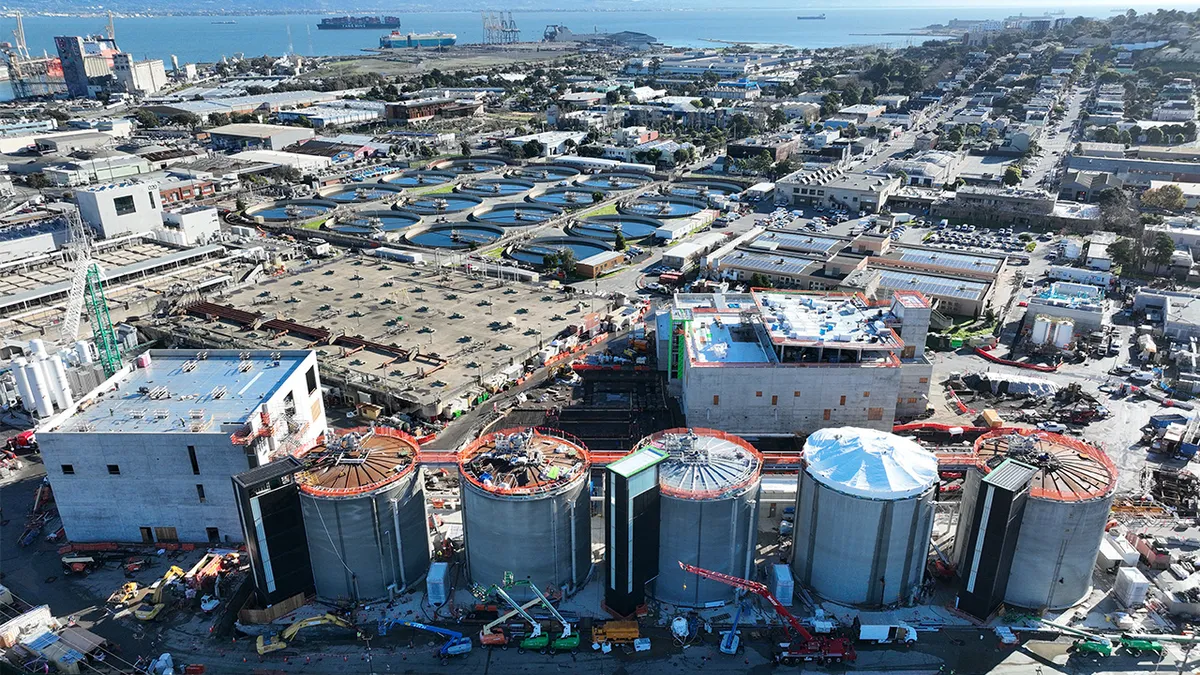 A broad, overhead shot of a water treatment facility, with thick silos and pools of water.