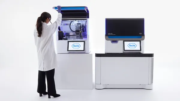 A scientist in a white jacket opens a Roche Axelios 1 next-generation sequencing machine.