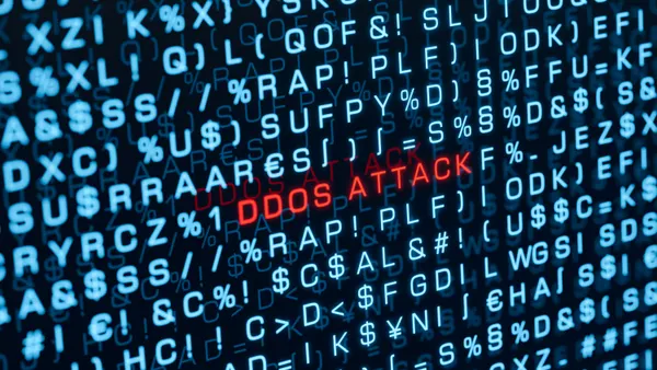 The words ddos attack are spelled out in red on a computer screen amid random blue text.