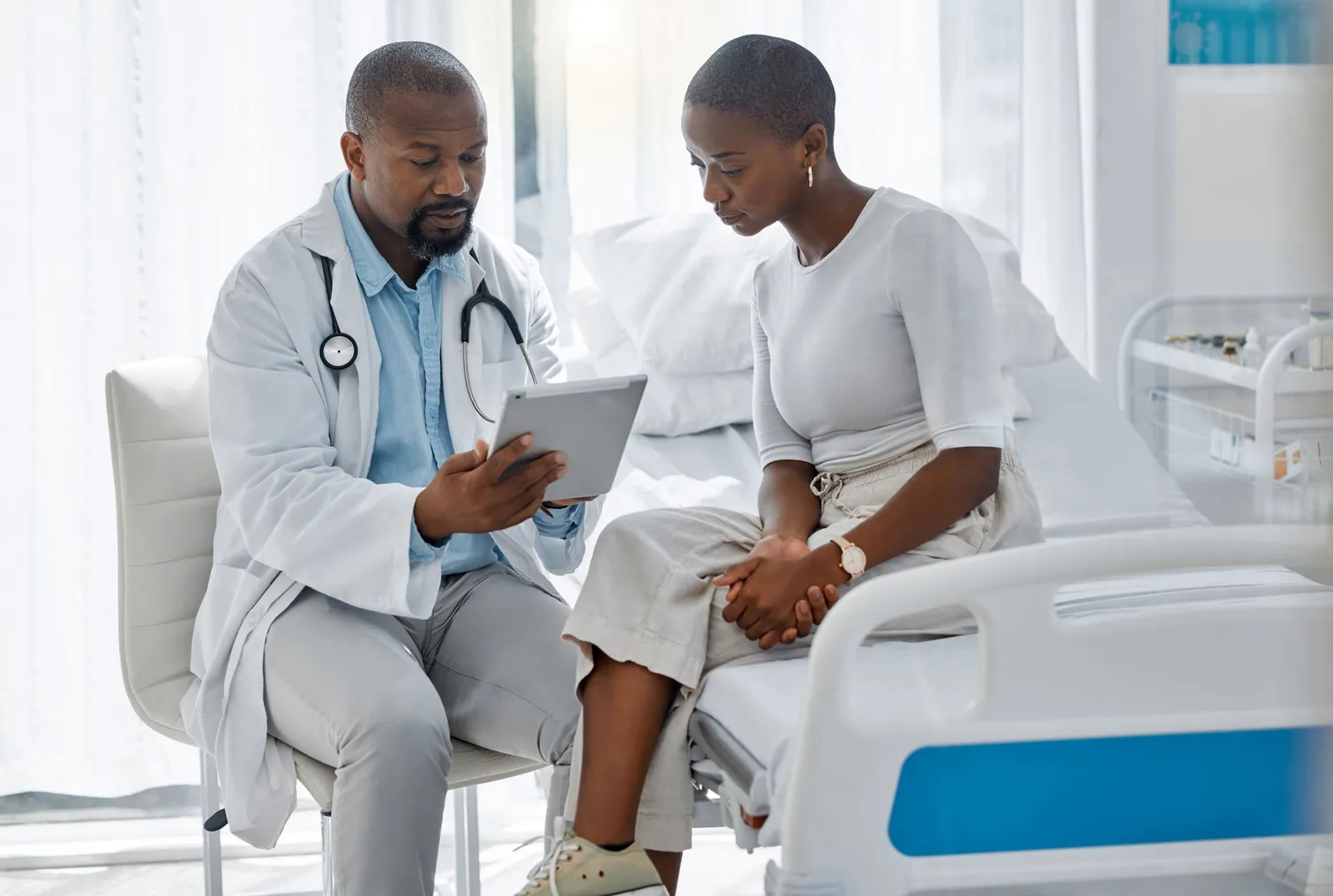 Doctor discussing information with a patient in a hospital room setting.