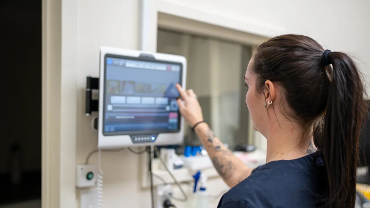 A female nurse operates a touch screen in a medical clinic.