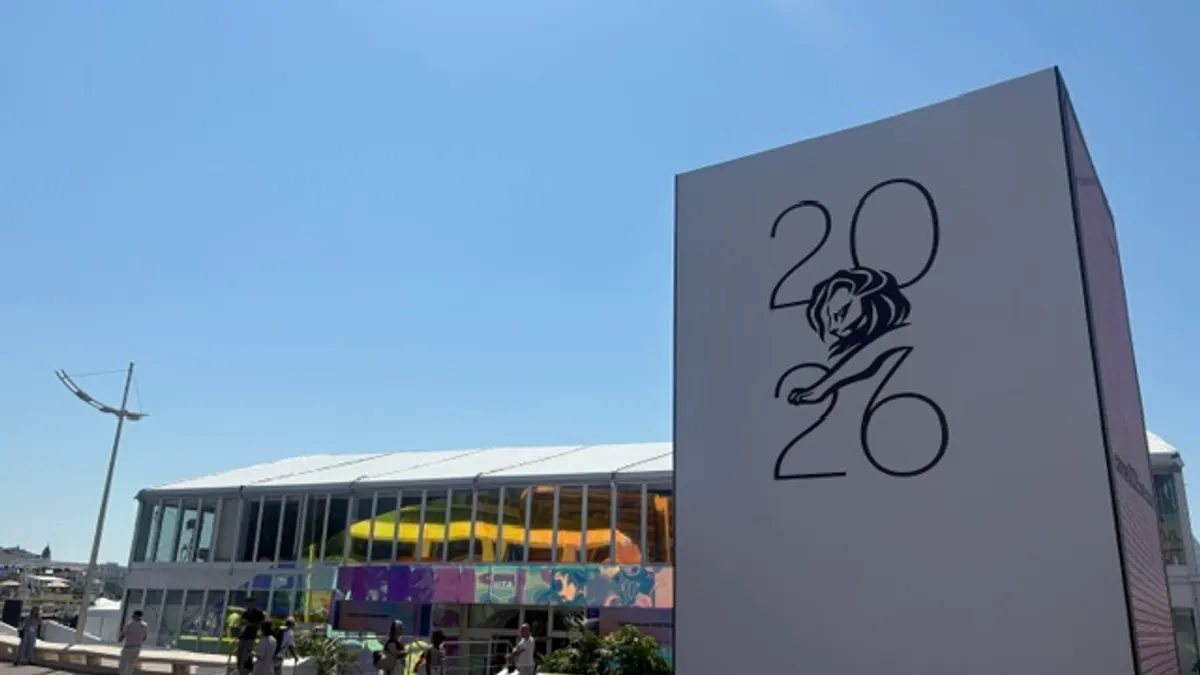 A sign for Cannes Lions stands on a beach promenade in Cannes, France