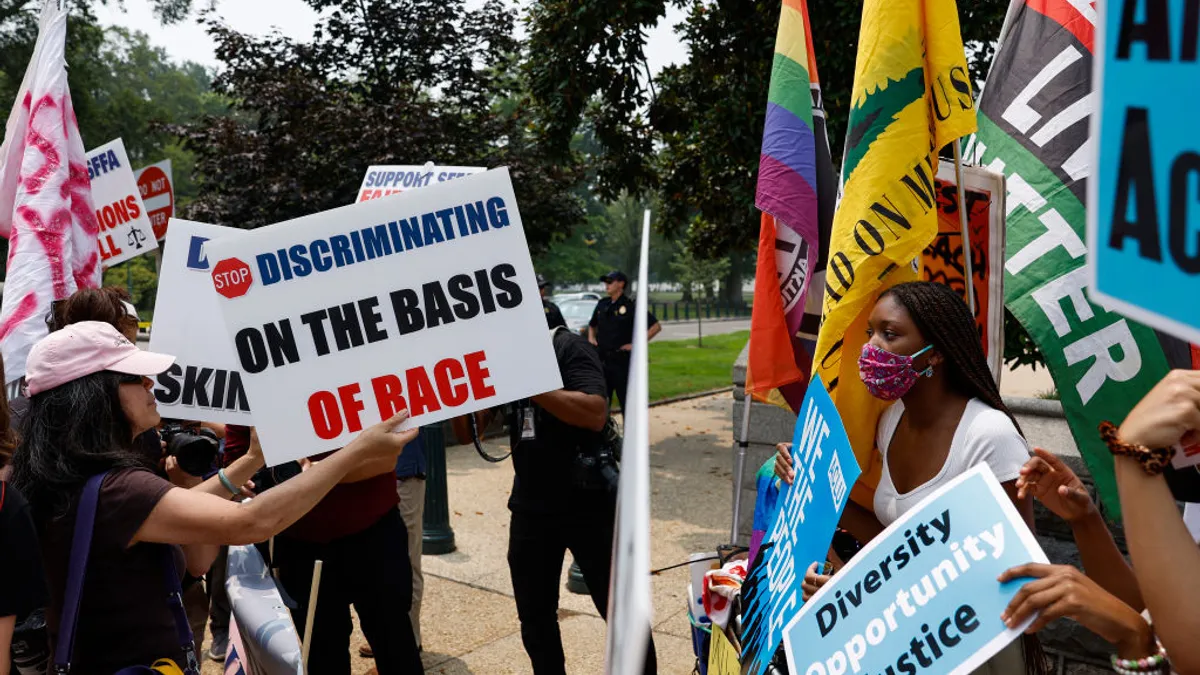 Protesters meet across a barrier line with differing signs.