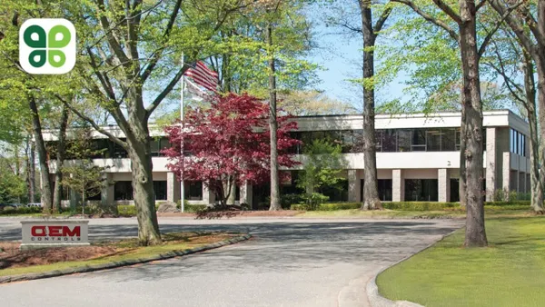 The exterior of OEM Controls' facility with a driveway and trees in the foreground.