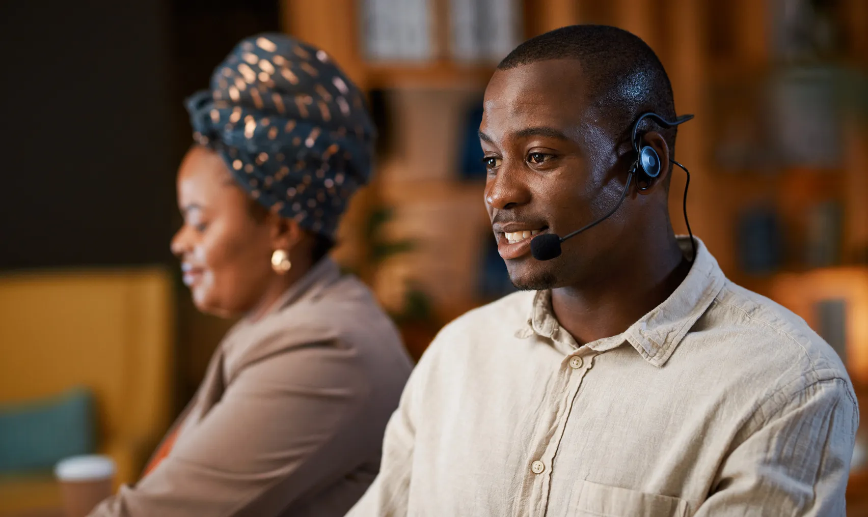 Two contact center agents talk on headsets.