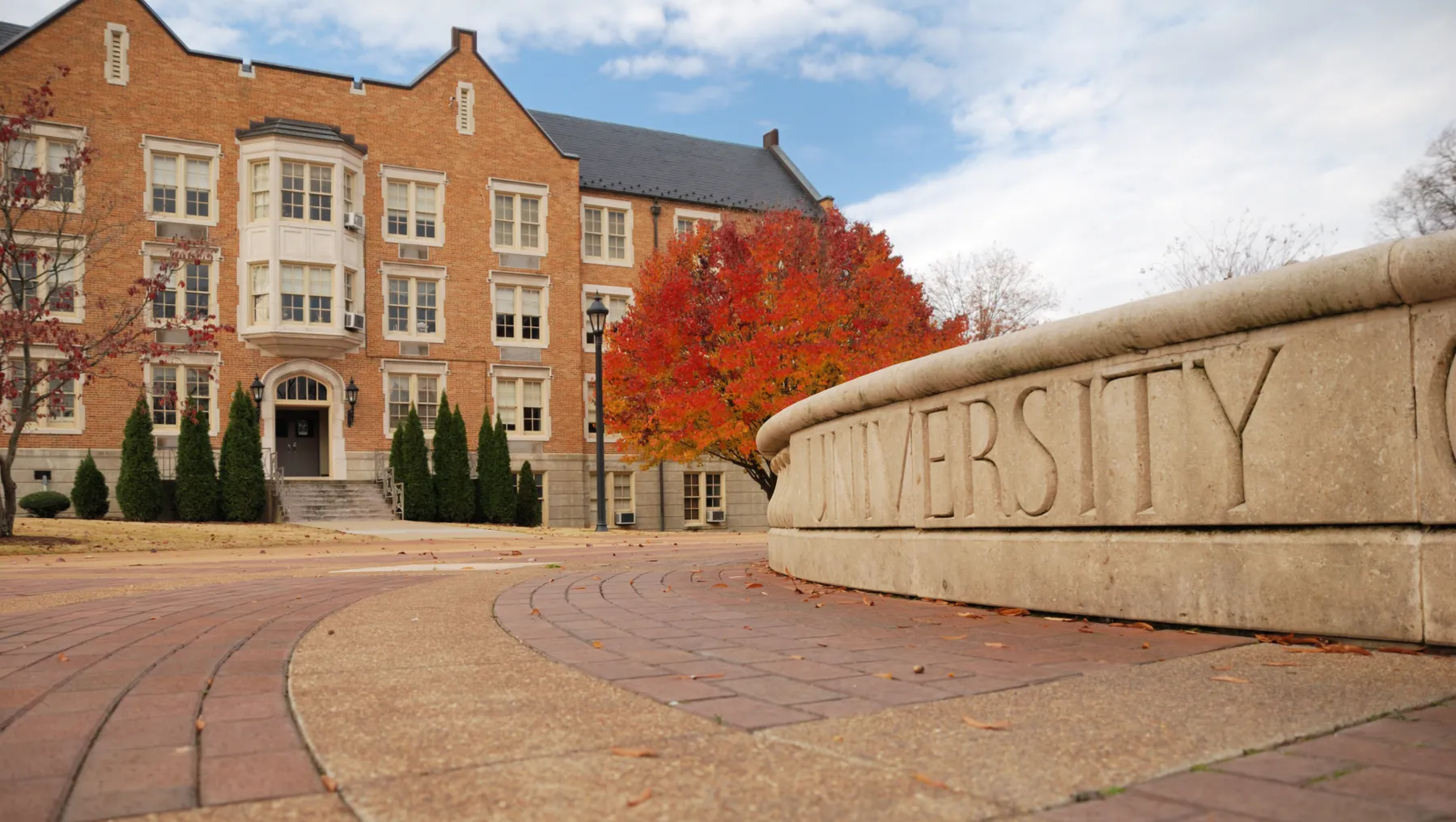 A college campus with a building in the background during fall.