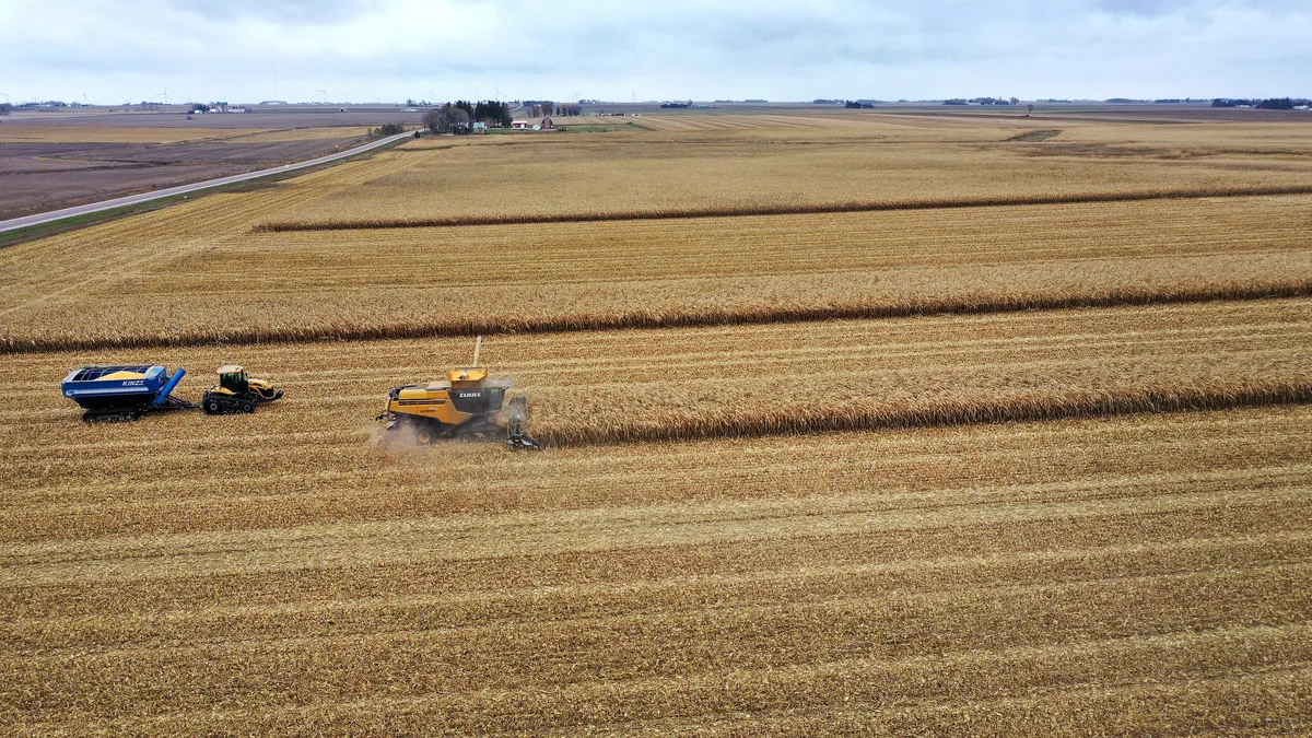 Tractors are seen in a corn field in an aerial shot.