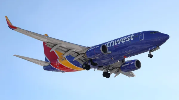 A red, yellow and blue plan soars through clear skies