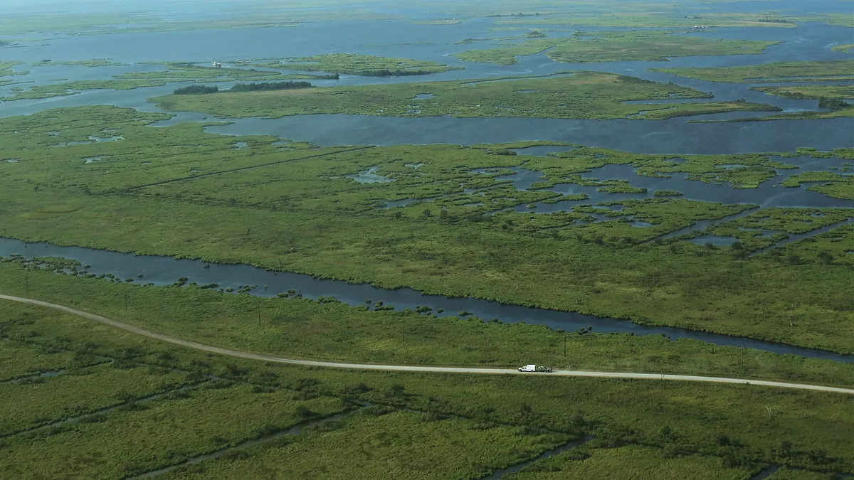 A truck drives along deteriorating wetlands in Plaquemines Parish, Louisiana.