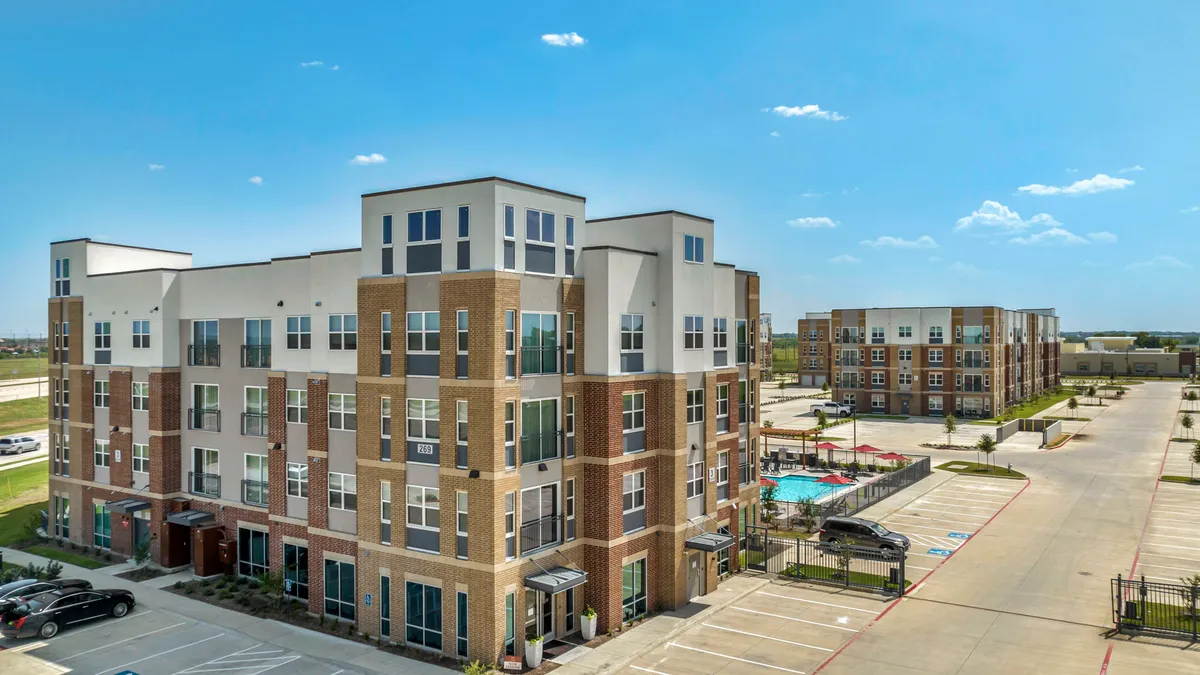 Two mid-rise apartment buildings separated by a parking area.