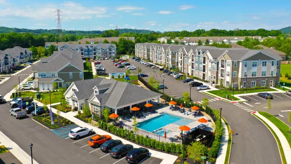 An overhead view of three-story buildings with sloped roofs, surrounding a pool.