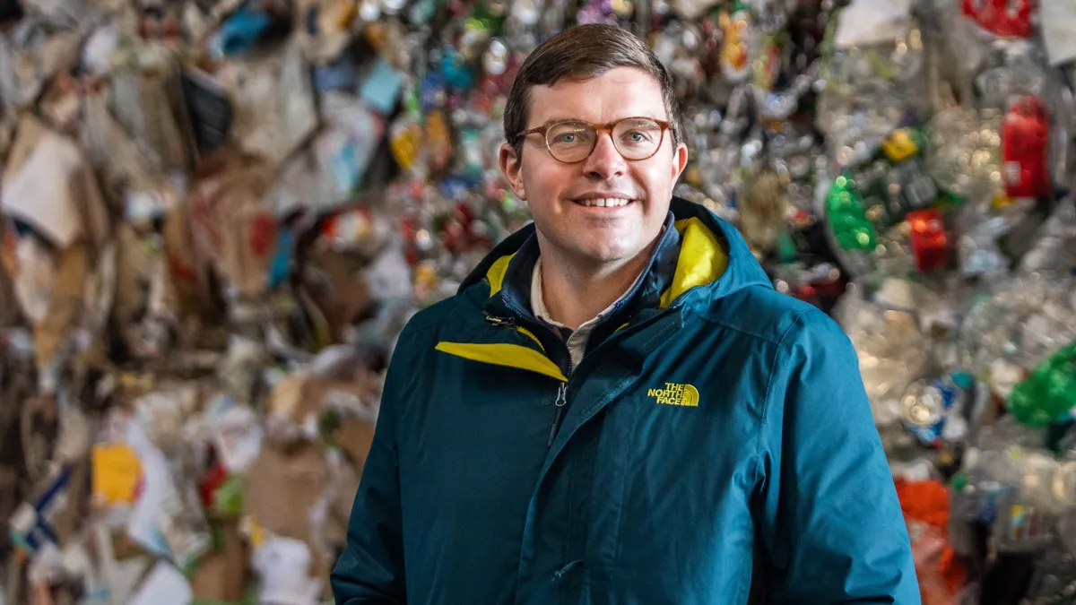 Person in jacket and glasses standing in front of baled recyclables