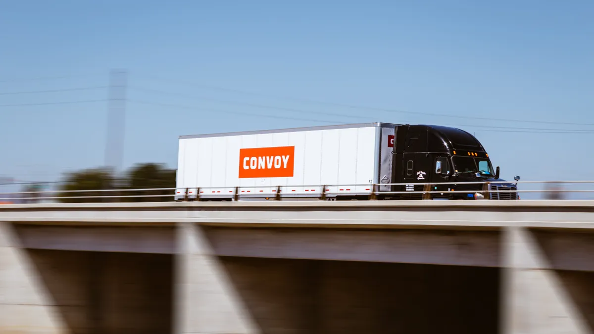 A truck hauling a Convoy trailer on a highway.