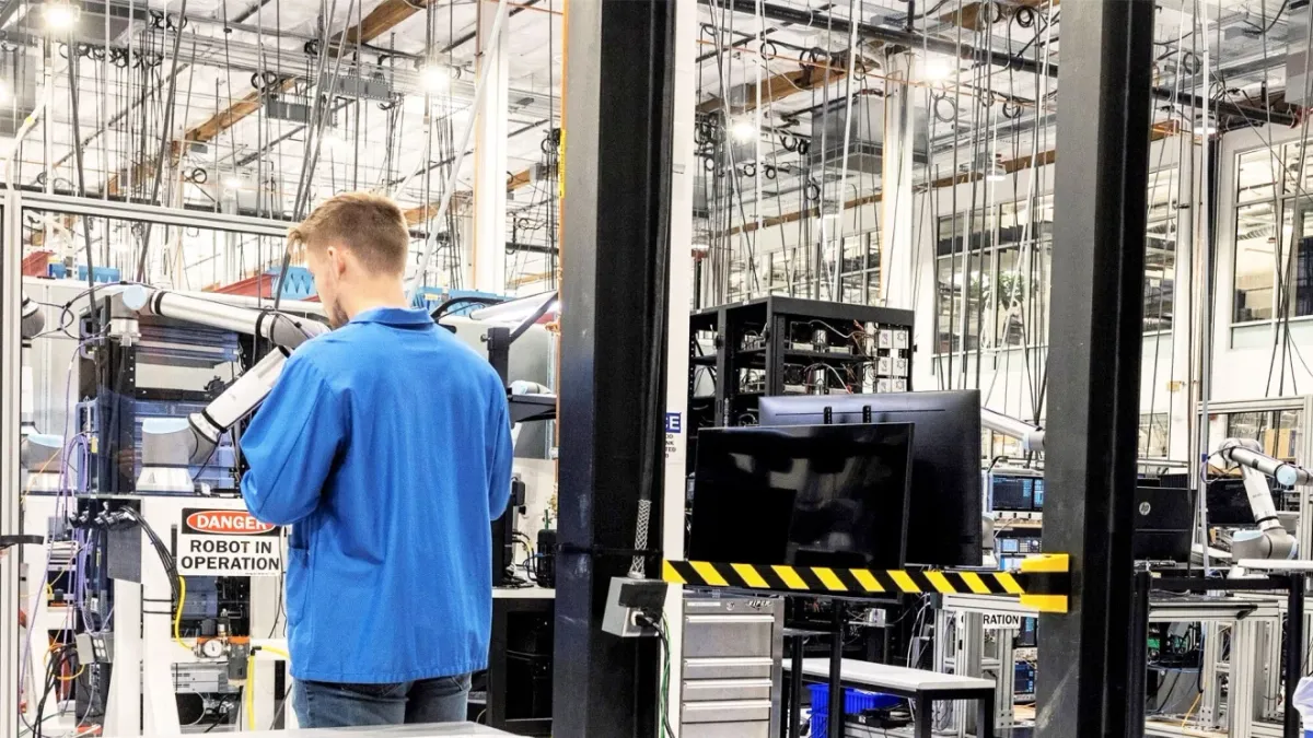 A man uses a machine in an manufacturing facility.