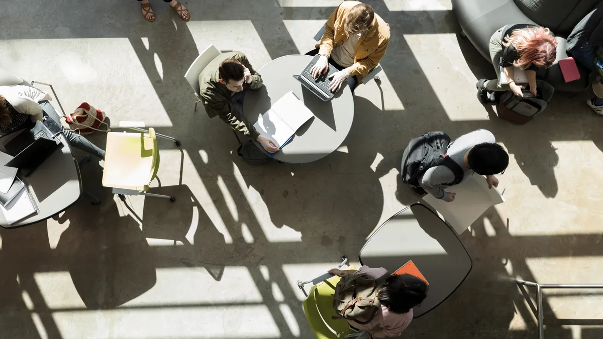 Aerial shot of college students working at tables in a sunny room